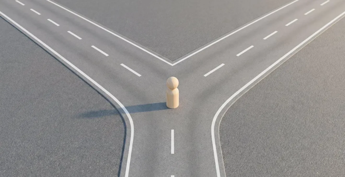 Vue aérienne d'une figurine en bois face à un carrefour en Y, symbolisant le choix entre assurance groupe et délégation.